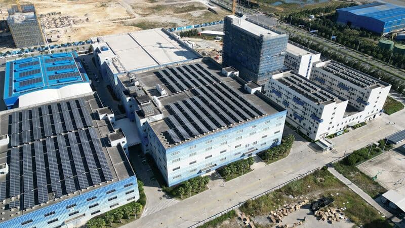 Aerial photograph of a factory campus with solar panels on its roofs.